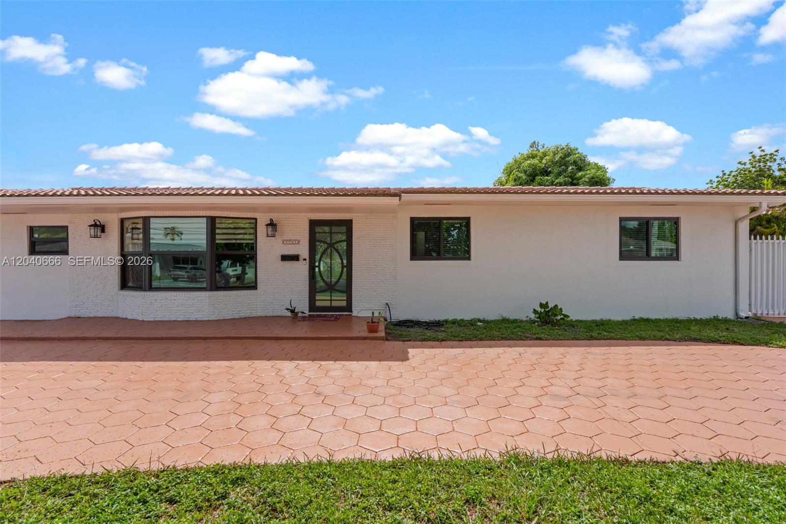 A single-story house features a white brick facade, a tiled roof, and a paved driveway — 7701 W 16th Ct, Hialeah FL 33014, HIALEAH, FL