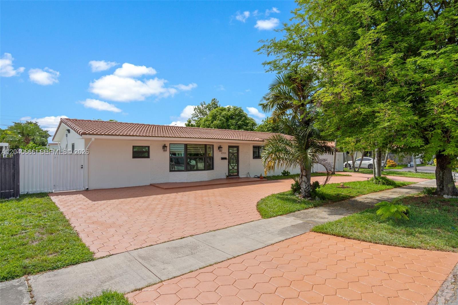 A single-story house with a white brick facade, a tiled roof, and a paved driveway — 7701 W 16th Ct, Hialeah FL 33014, HIALEAH, FL
