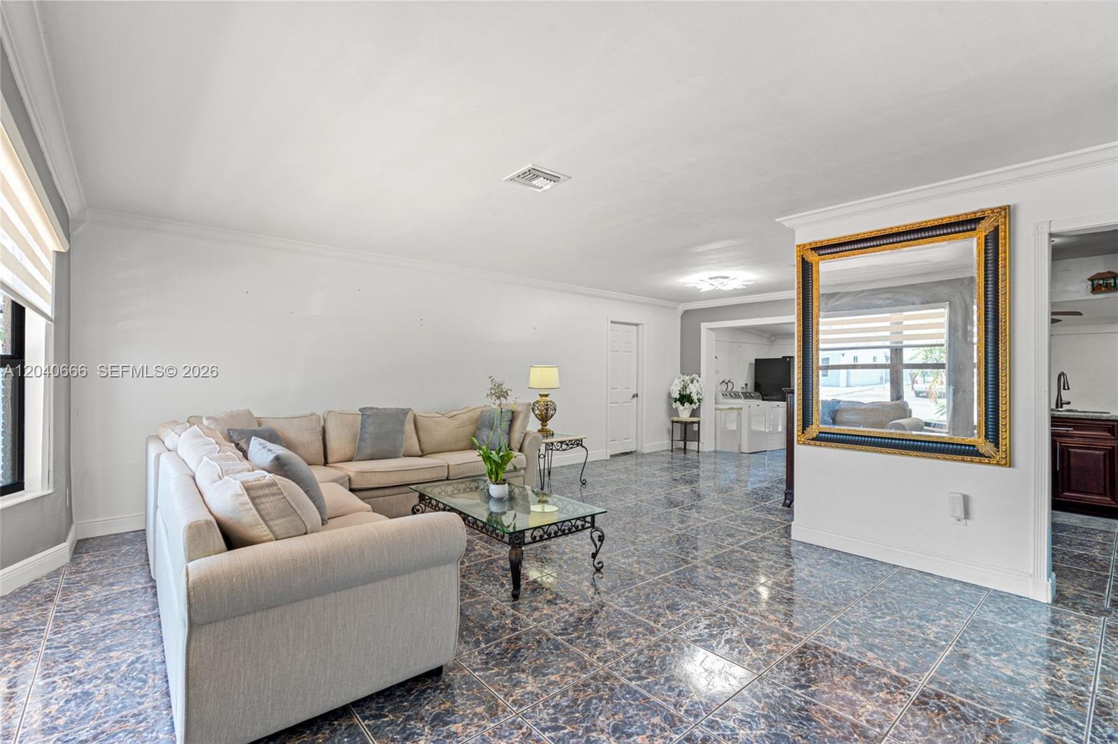 A living room features a beige sectional sofa, a glass coffee table, and dark tile flooring — 7701 W 16th Ct, Hialeah FL 33014, HIALEAH, FL