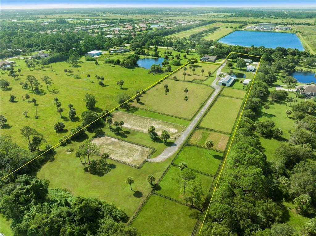 An aerial view shows a fenced equestrian property with pastures, a driveway, and outbuildings — 8530 8th Street, Vero Beach FL 32968, VERO BEACH, FL