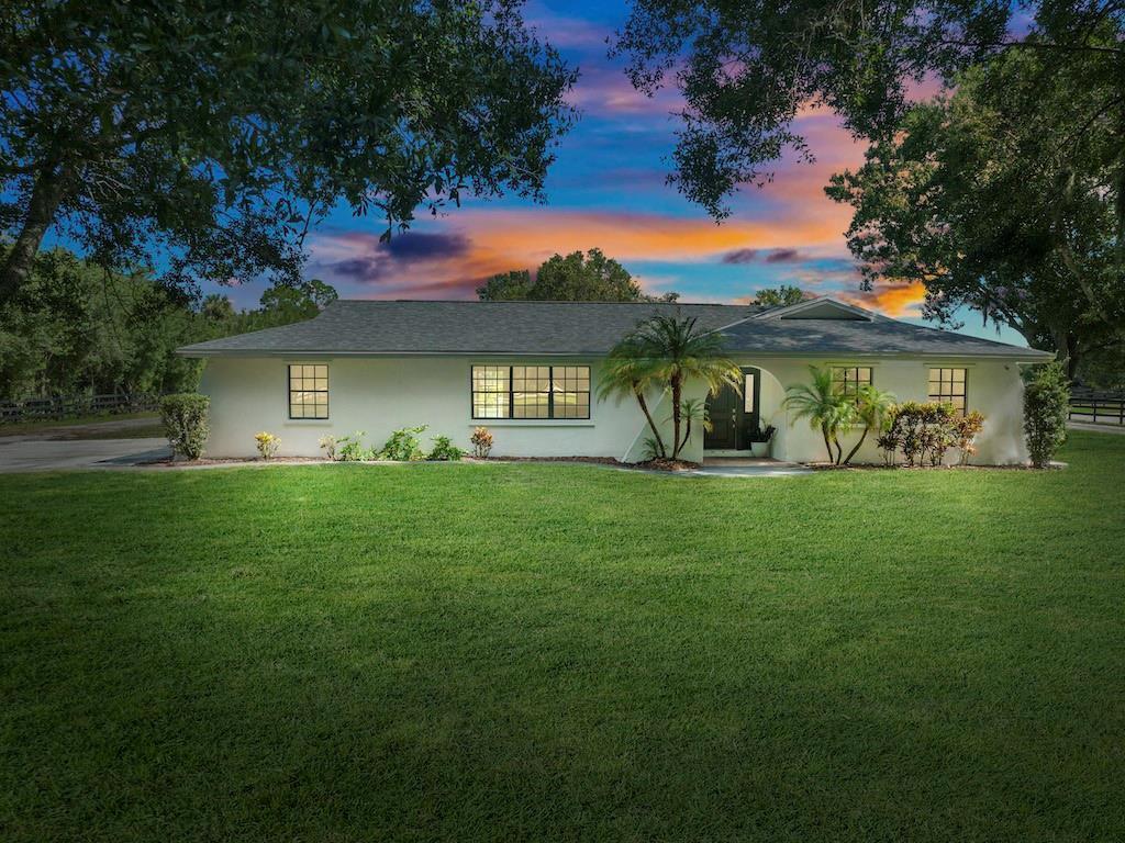 A single-story white house with a dark roof sits behind a large, manicured green lawn — 8530 8th Street, Vero Beach FL 32968, VERO BEACH, FL