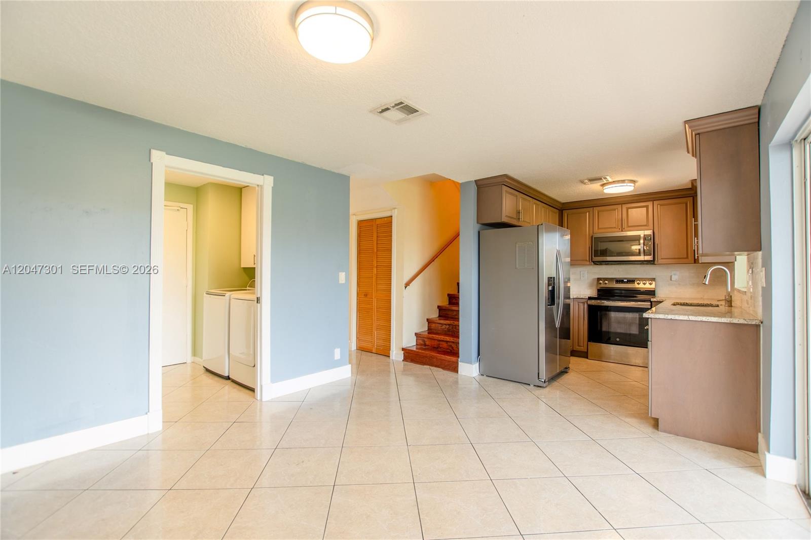 This kitchen and laundry area features tile flooring, wood cabinets, and stainless steel appliances — 9803 NW 37th St, Sunrise FL 33351, SUNRISE, FL