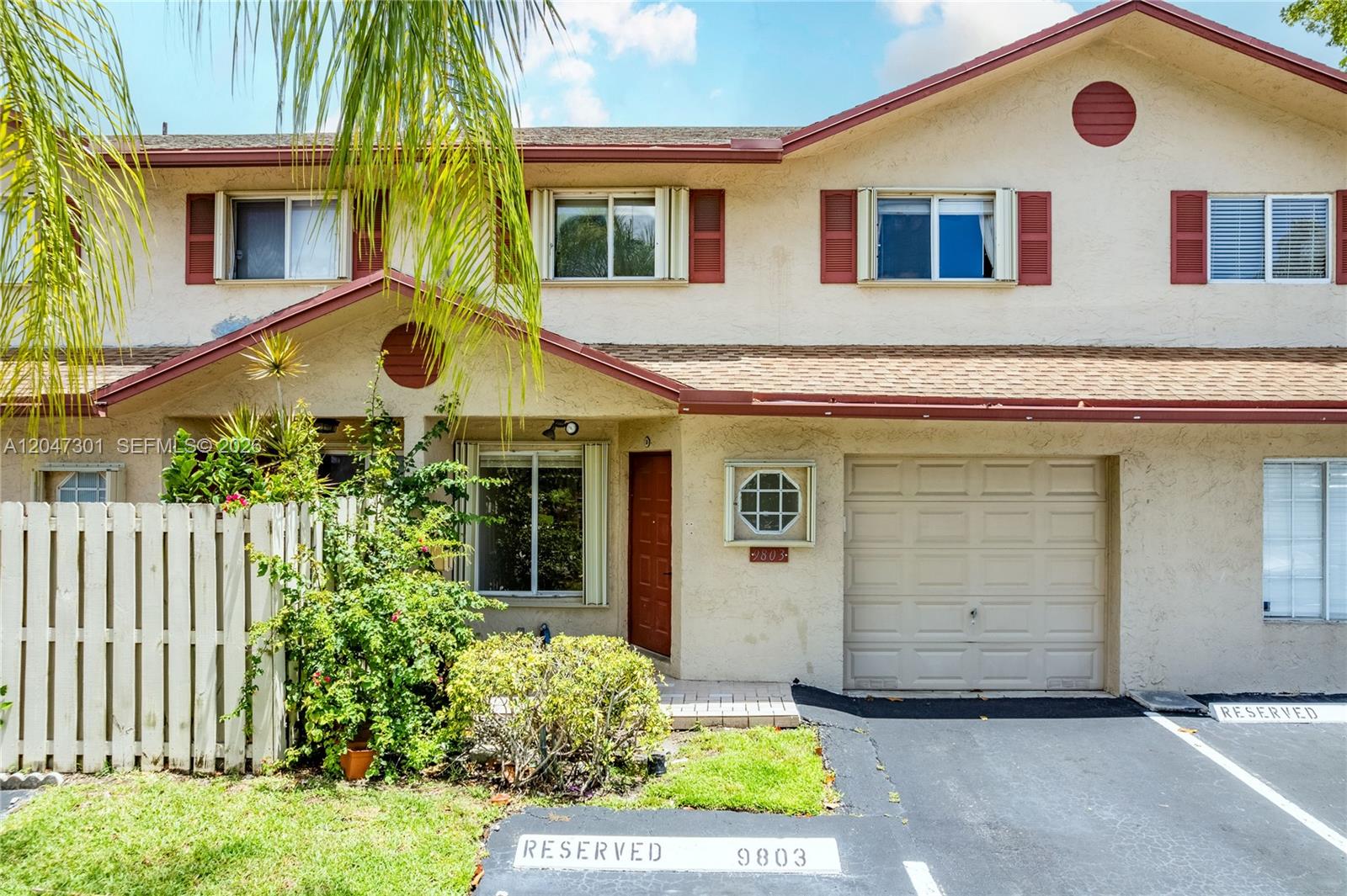 A two-story townhouse features a tan stucco exterior, a garage, and a reserved parking space — 9803 NW 37th St, Sunrise FL 33351, SUNRISE, FL