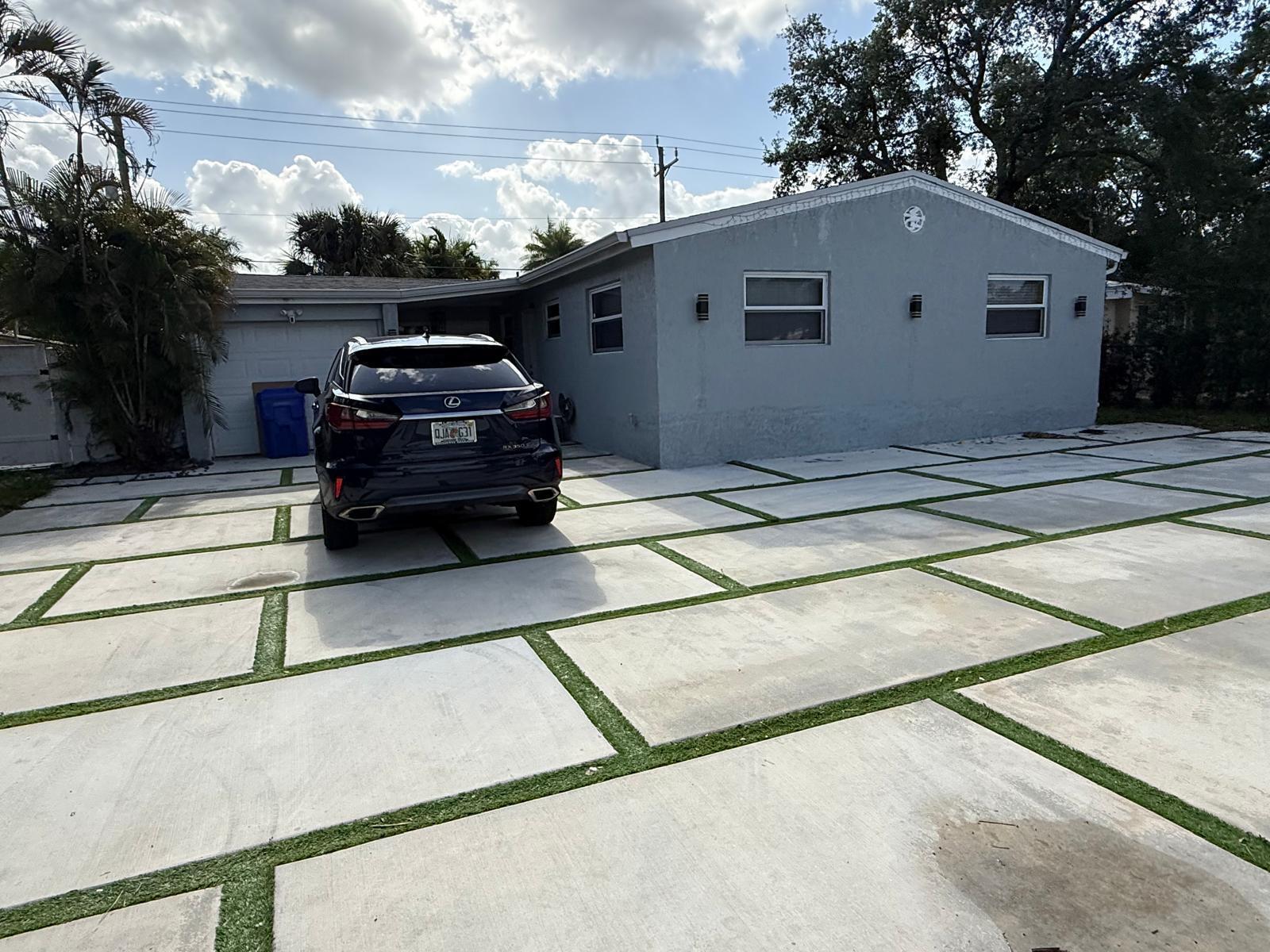 A gray house features a large concrete paver driveway with grass strips and a parked car — 3111 N 66th Avenue, Hollywood FL 33024, HOLLYWOOD, FL