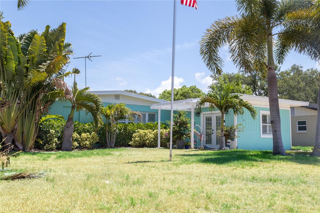 A light blue single-story house with a white pergola and palm trees in the yard — 136 MARYLAND AVENUE, PALM HARBOR, FL