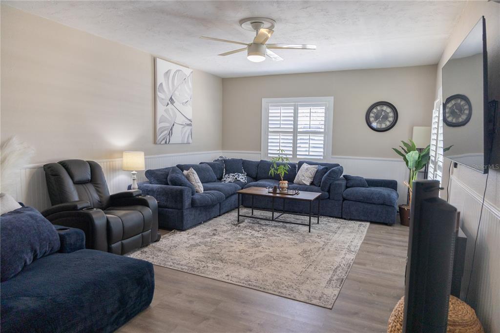 A living room features a blue sectional sofa, a recliner, and a central area rug — 136 MARYLAND AVENUE, PALM HARBOR, FL