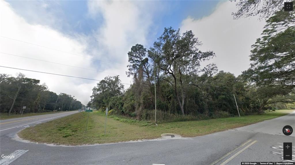 A vacant, tree-covered corner lot sits at the intersection of two paved roads — 0 BROAD STREET, BROOKSVILLE, FL