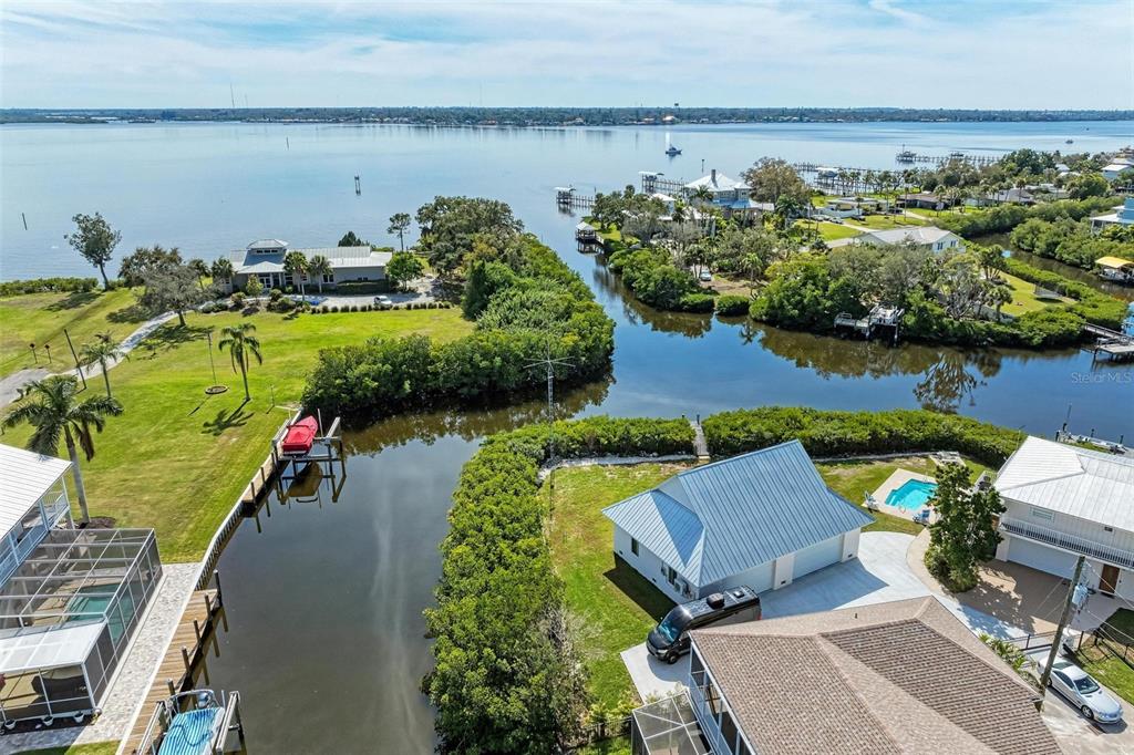 An aerial view shows waterfront homes, a canal, and a large body of water — 3311 WATER STREET, ELLENTON, FL