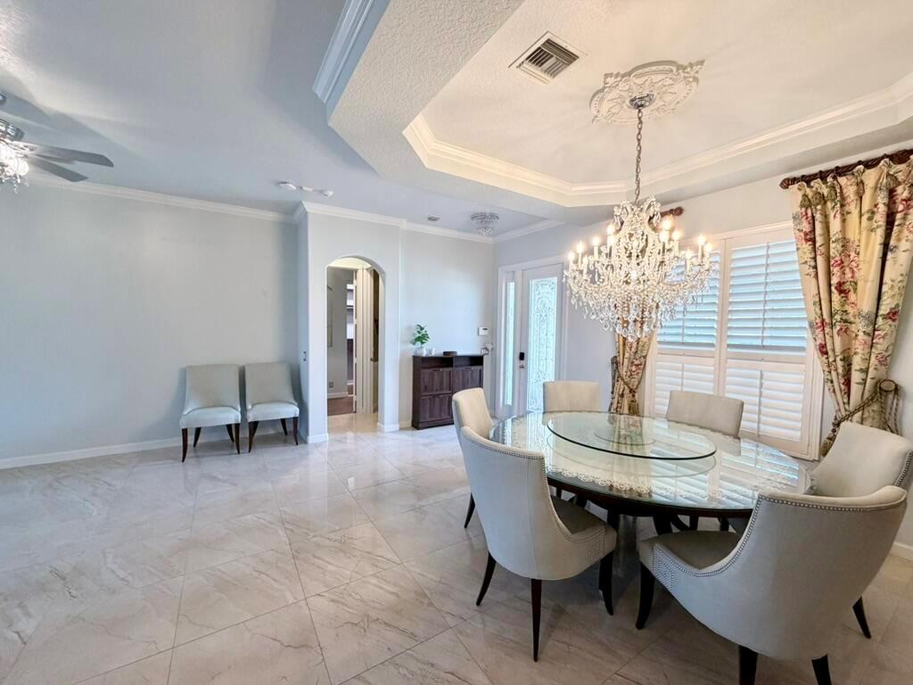 A dining room features a crystal chandelier, a glass-topped table, and light-colored tile flooring — 9546 LANTERN BAY Circle, West Palm Beach FL 33411, WEST PALM BEACH, FL