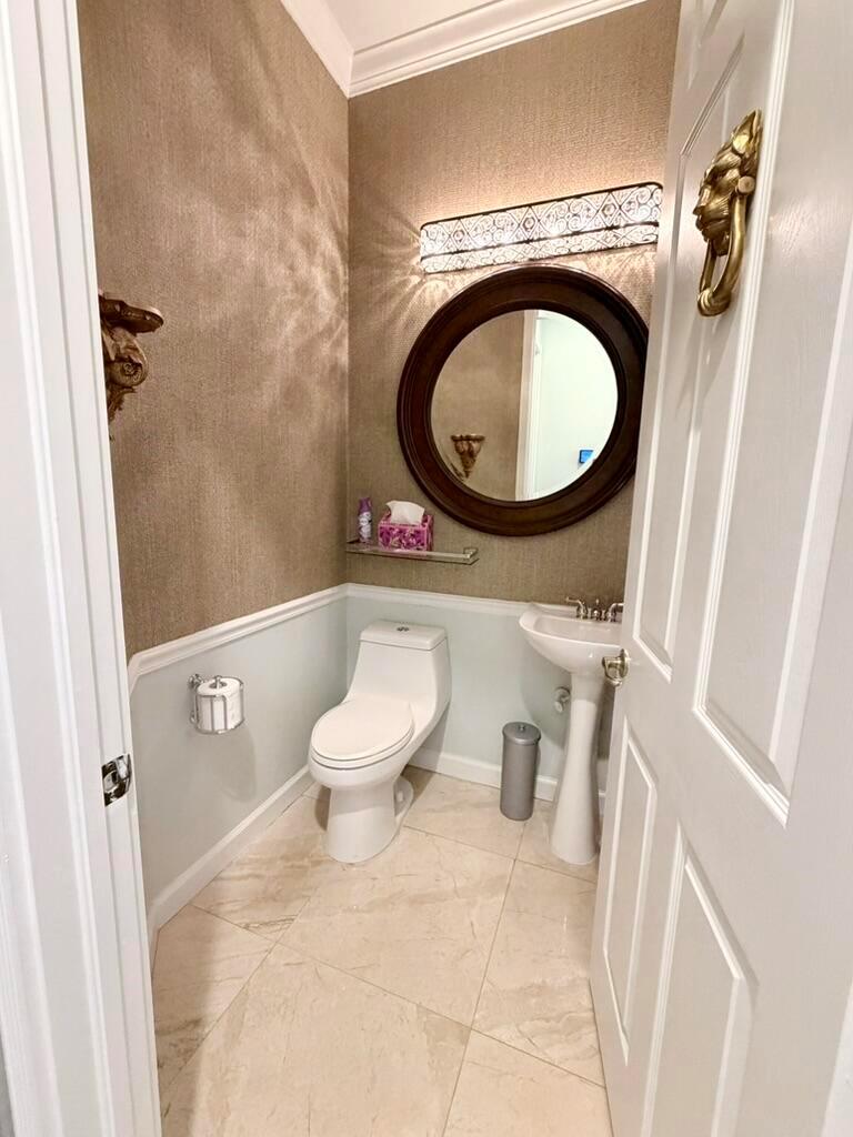 A small powder room features a pedestal sink, toilet, round mirror, and two-toned wall finishes — 9546 LANTERN BAY Circle, West Palm Beach FL 33411, WEST PALM BEACH, FL