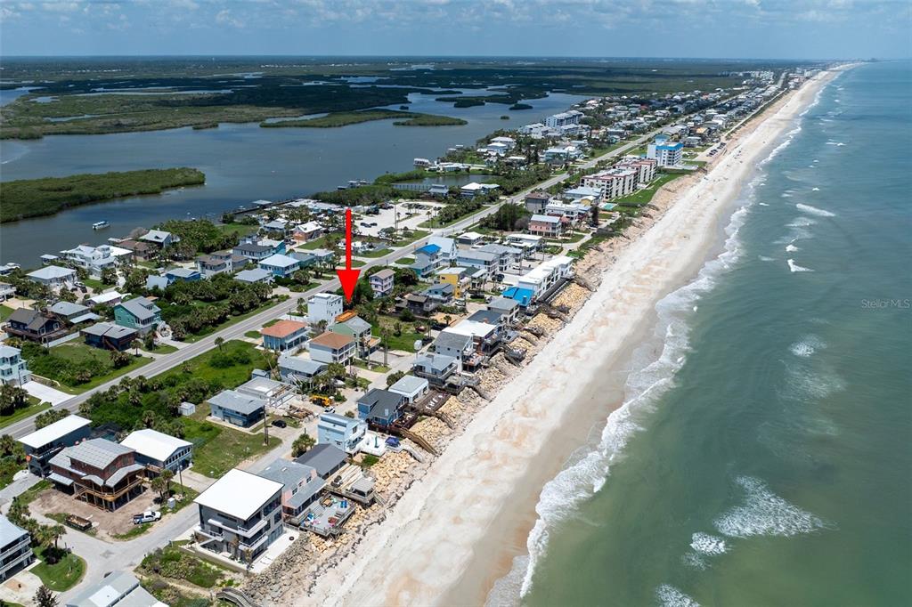 An aerial view shows a coastal neighborhood with houses situated along a sandy beach — 6854 S ATLANTIC AVENUE, NEW SMYRNA BEACH, FL