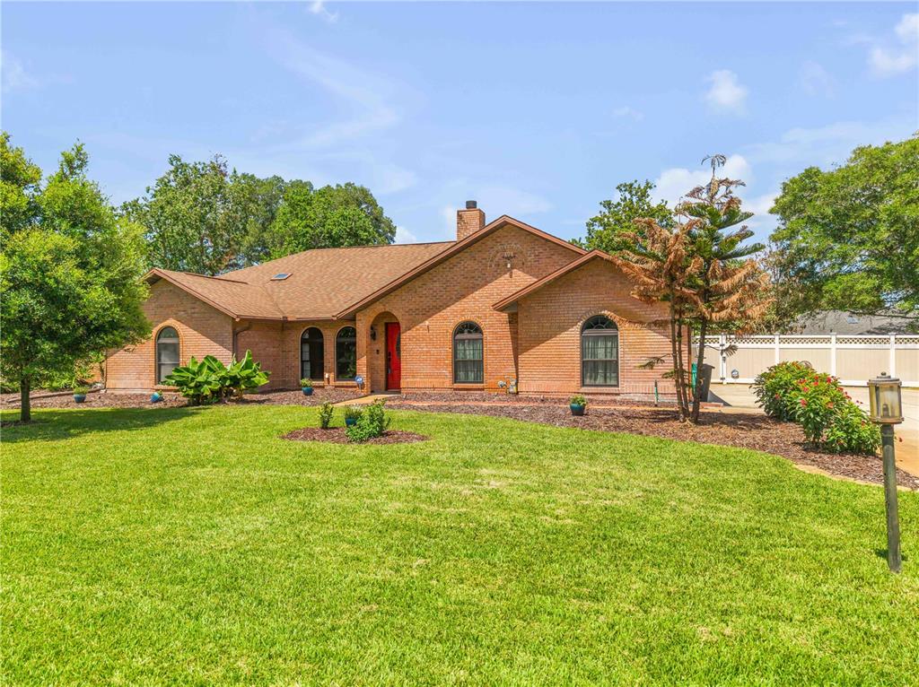 A single-story brick house with a red front door and a large front lawn — 171 LIVE OAK COURT, NEW SMYRNA BEACH, FL