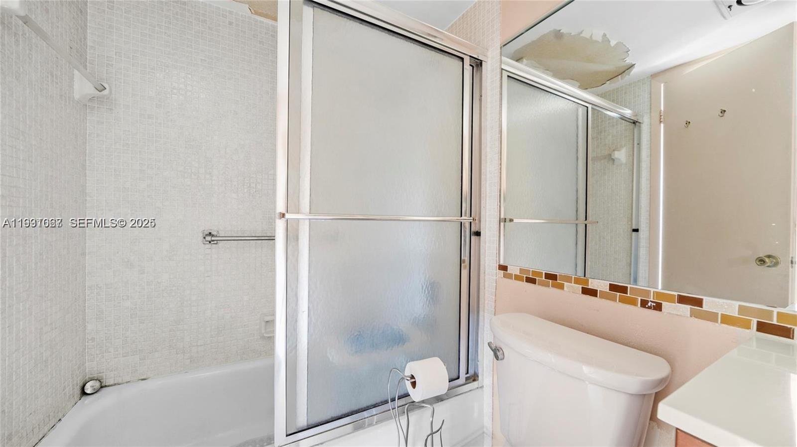 A bathroom features a tiled shower with a glass door, a toilet, and a mirror — 79 Suffolk B # 79, Boca Raton FL 33434, BOCA RATON, FL