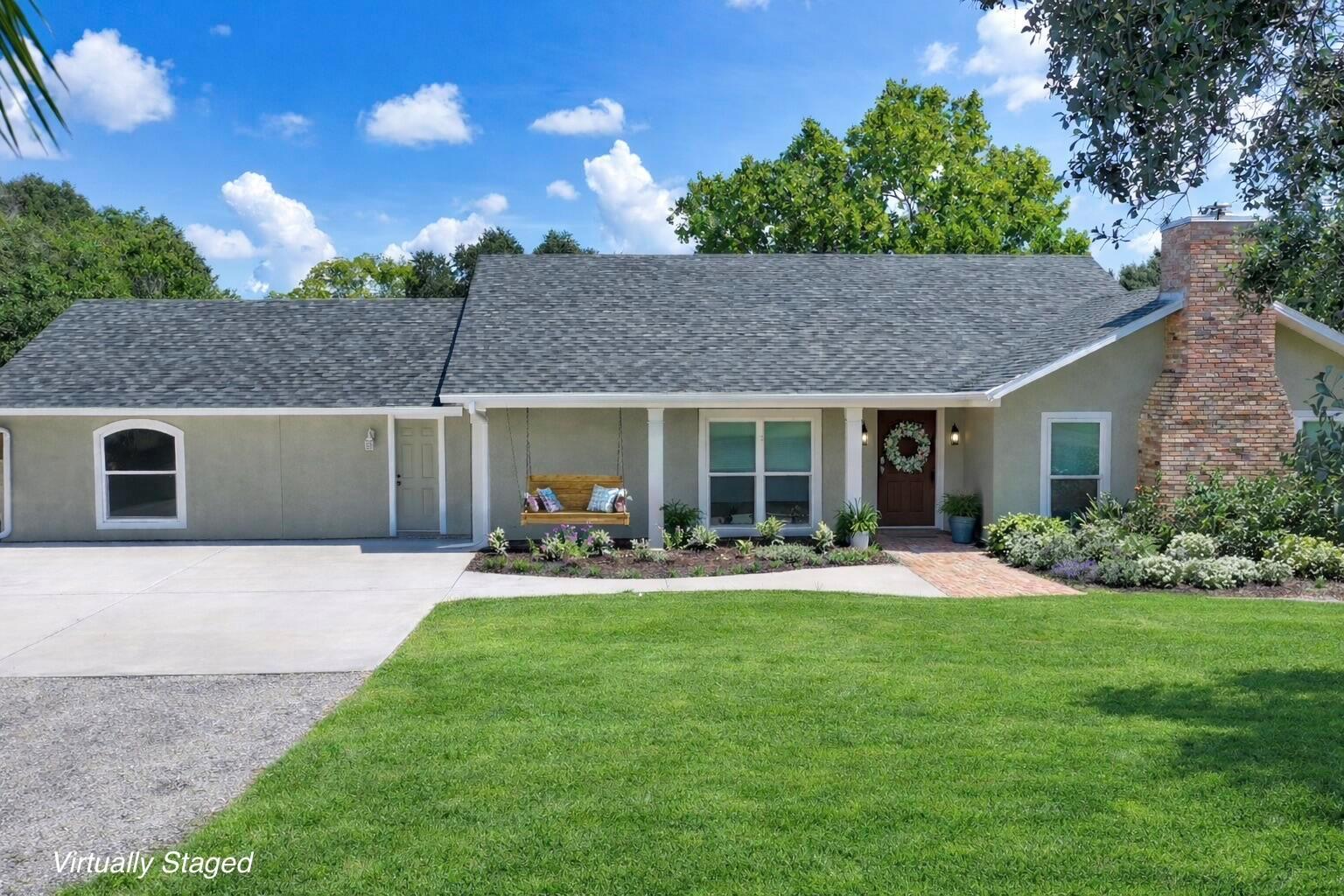 A single-story house with a brick chimney, a front porch swing, and a paved driveway — 6080 65th Street, Vero Beach FL 32967, VERO BEACH, FL