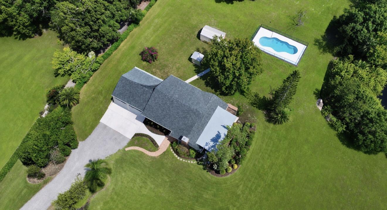 An aerial view shows a house with a gray roof, a pool, and surrounding trees — 6080 65th Street, Vero Beach FL 32967, VERO BEACH, FL
