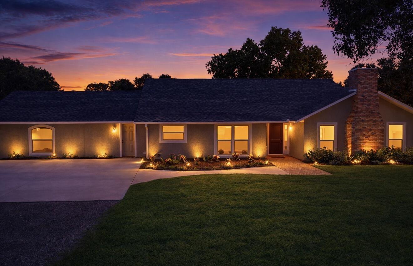 A single-story house with a brick chimney and landscape lighting at dusk — 6080 65th Street, Vero Beach FL 32967, VERO BEACH, FL