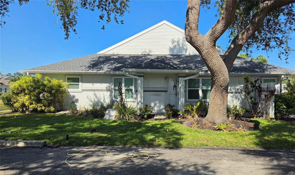 A single-story residential building with a gray roof, light-colored walls, and a large tree — 11009 JASMINE CIRCLE, BRADENTON, FL