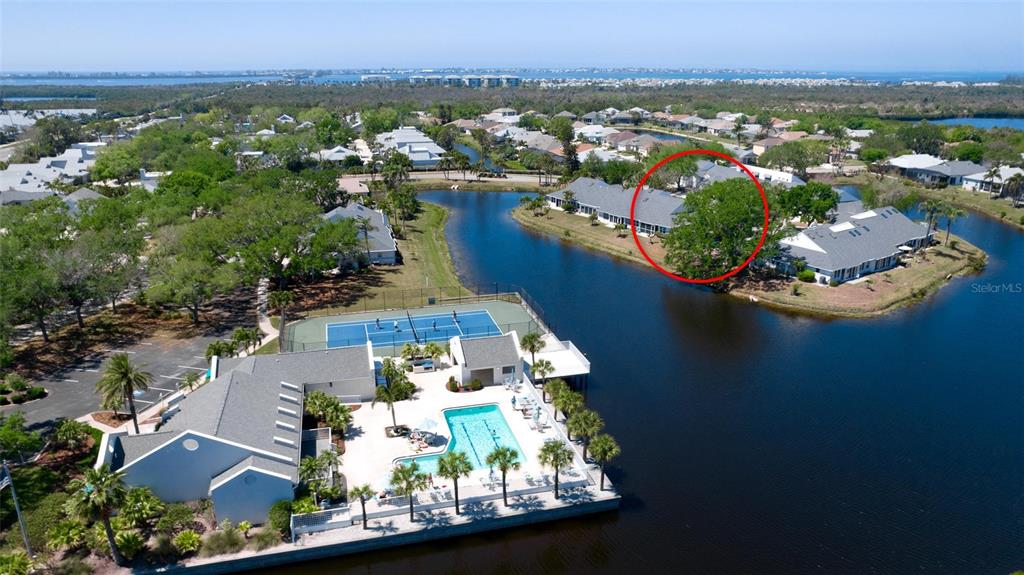 An aerial view shows a residential community with a pool, tennis court, and lake — 11009 JASMINE CIRCLE, BRADENTON, FL