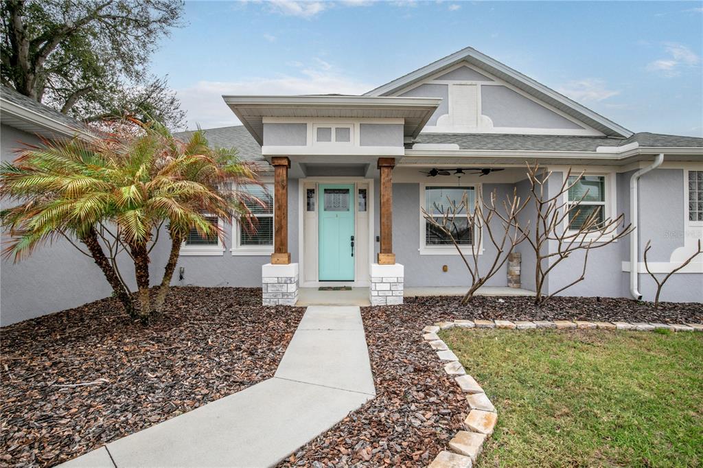 A gray house with a light blue front door, wooden pillars, and a palm tree — 36452 GRAND ISLAND OAKS CIRCLE, GRAND ISLAND, FL