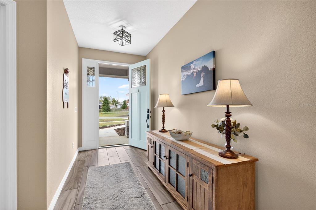 A foyer features a light blue front door, wood-look tile flooring, and a wooden console table — 36452 GRAND ISLAND OAKS CIRCLE, GRAND ISLAND, FL