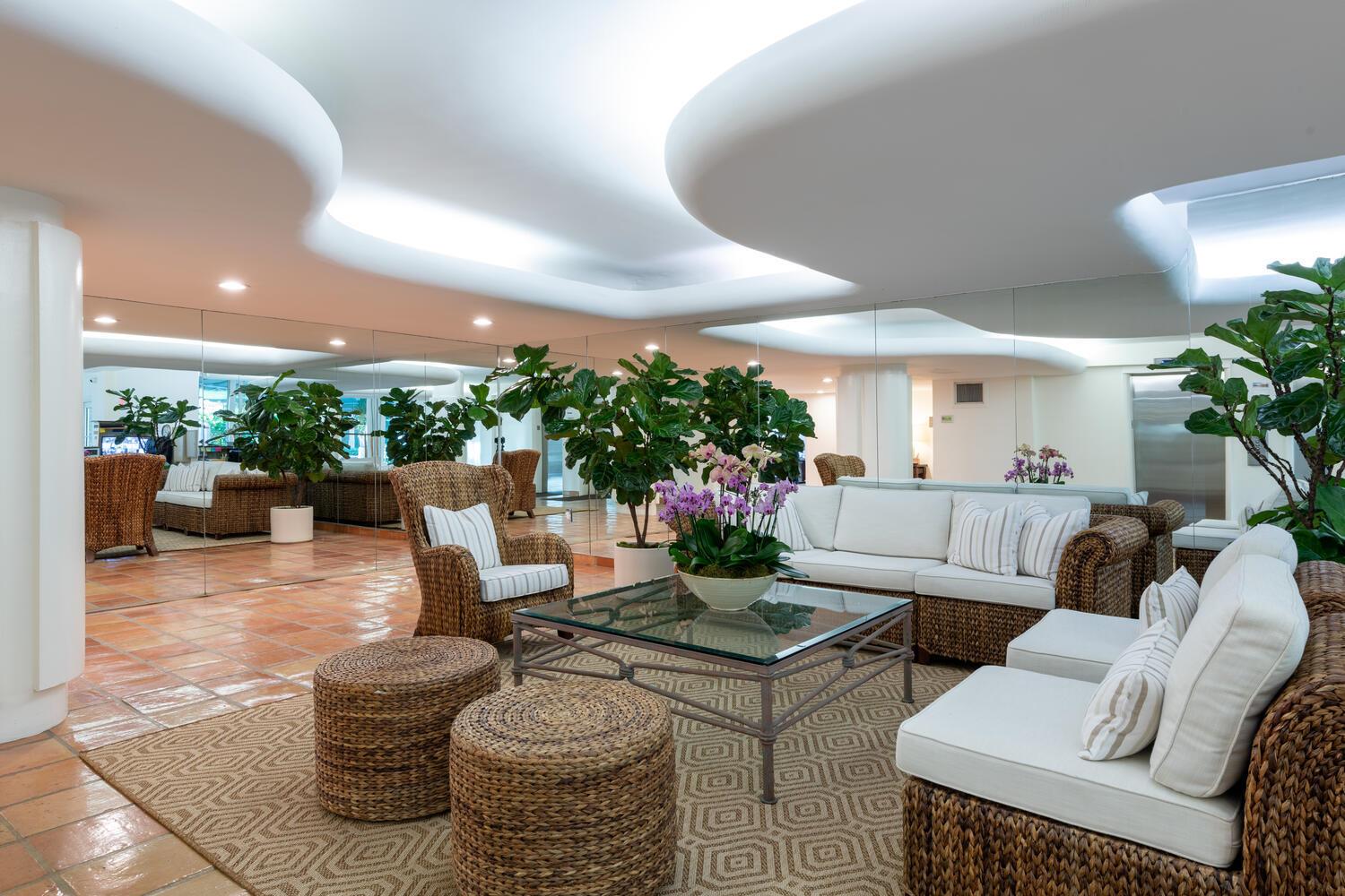 A lobby seating area features wicker furniture, a glass coffee table, and a mirrored wall — 170 N Ocean Boulevard # 511, Palm Beach FL 33480, PALM BEACH, FL