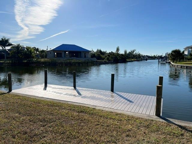 A wooden dock extends into a canal with a house under construction in the background — 15227 APPLETON BOULEVARD, PORT CHARLOTTE, FL