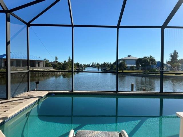 A swimming pool enclosed by a screen cage overlooks a canal with houses nearby — 15227 APPLETON BOULEVARD, PORT CHARLOTTE, FL