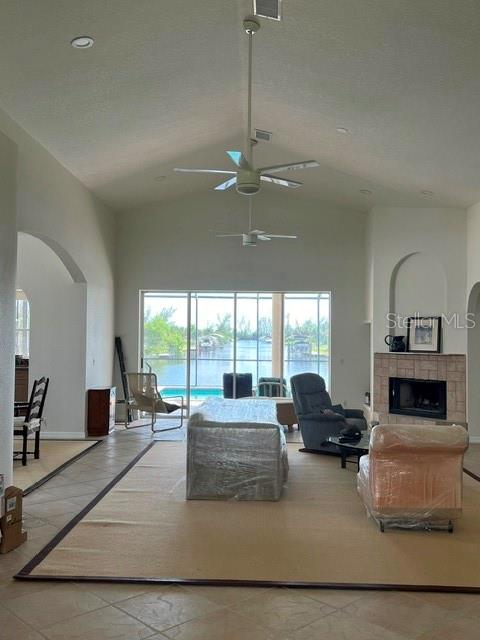 A living room features a vaulted ceiling, a ceiling fan, a fireplace, and large sliding doors — 15227 APPLETON BOULEVARD, PORT CHARLOTTE, FL