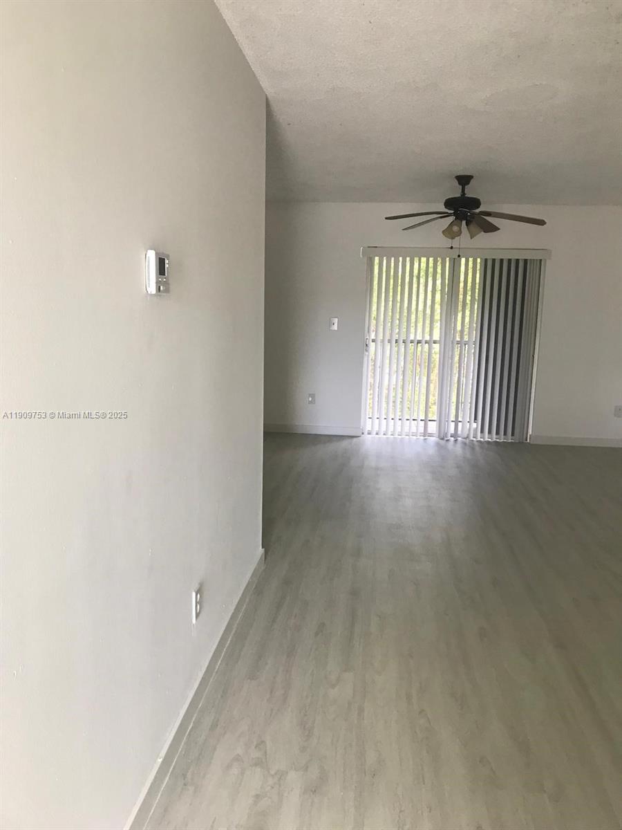An empty room features light-colored wood-look flooring, white walls, and a ceiling fan — 438 NE 210th Cir Ter # 4B, Miami FL 33179, MIAMI, FL