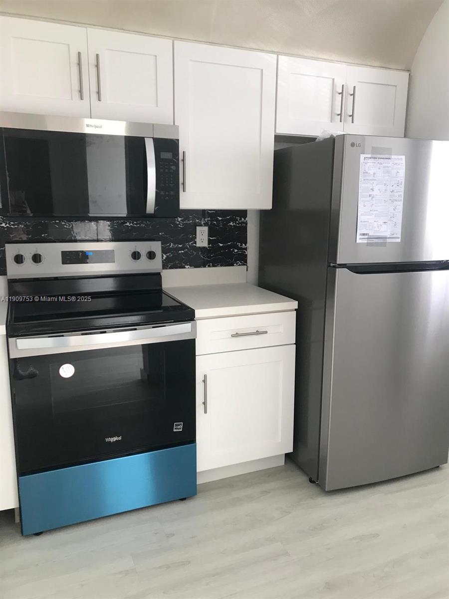 A kitchen features white cabinets, stainless steel appliances, and a black marble-patterned backsplash — 438 NE 210th Cir Ter # 4B, Miami FL 33179, MIAMI, FL