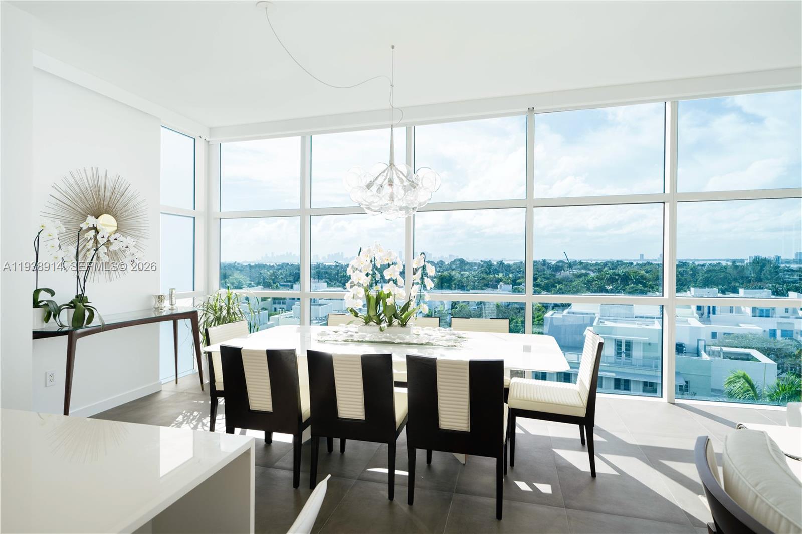 A dining room features a white table, modern chairs, and floor-to-ceiling windows with city views — 6103 Aqua Ave # 701, Miami Beach FL 33141, MIAMI BEACH, FL