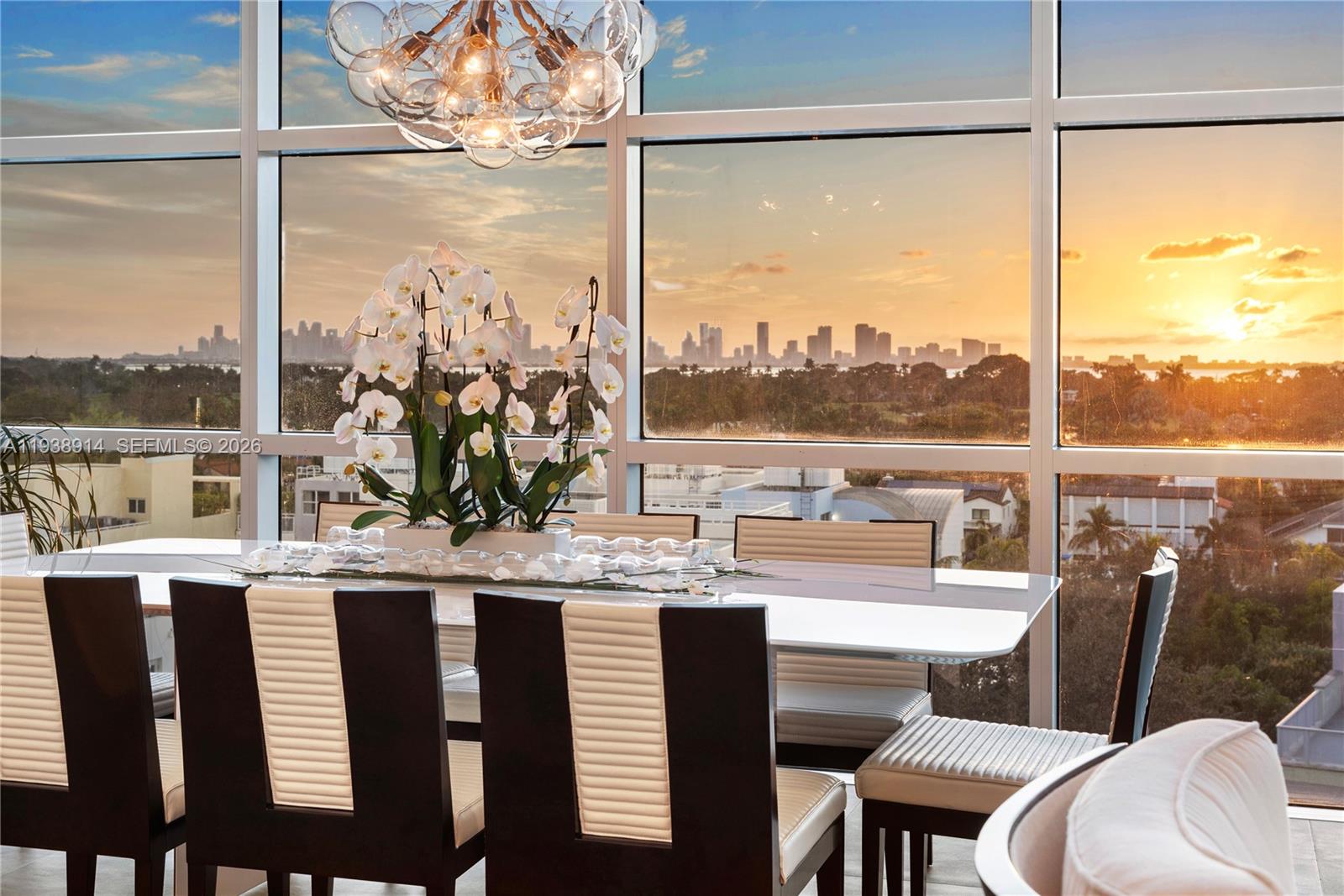 A dining room features a modern table, chairs, and floor-to-ceiling windows overlooking a city skyline — 6103 Aqua Ave # 701, Miami Beach FL 33141, MIAMI BEACH, FL