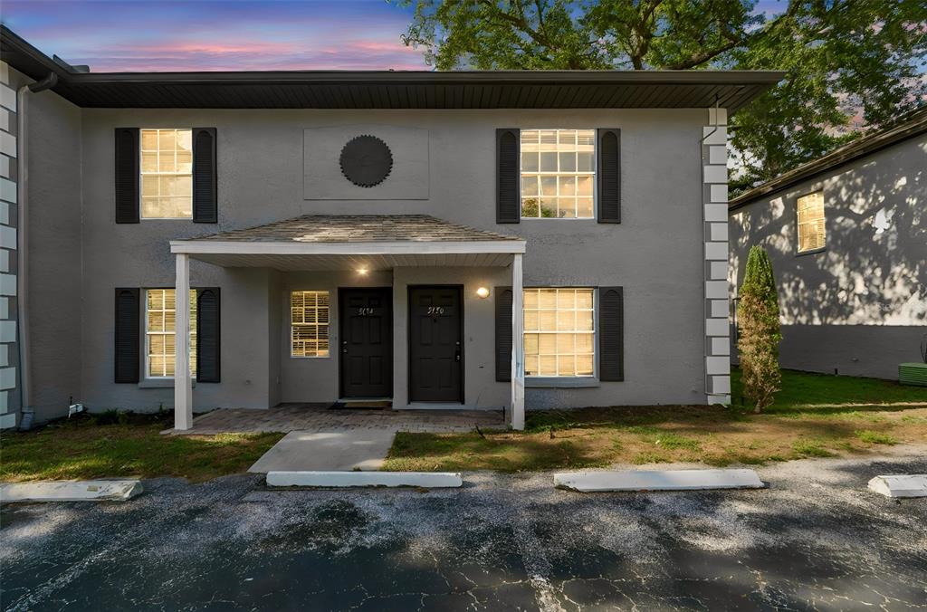 A two-story gray apartment building with a covered entryway and two black front doors — 5156 SUNRIDGE PALMS DRIVE, TAMPA, FL