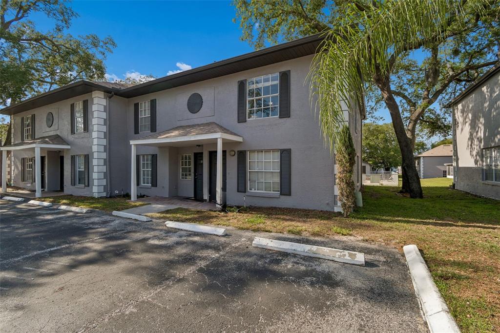 A two-story gray apartment building with a parking lot and covered entryways — 5156 SUNRIDGE PALMS DRIVE, TAMPA, FL