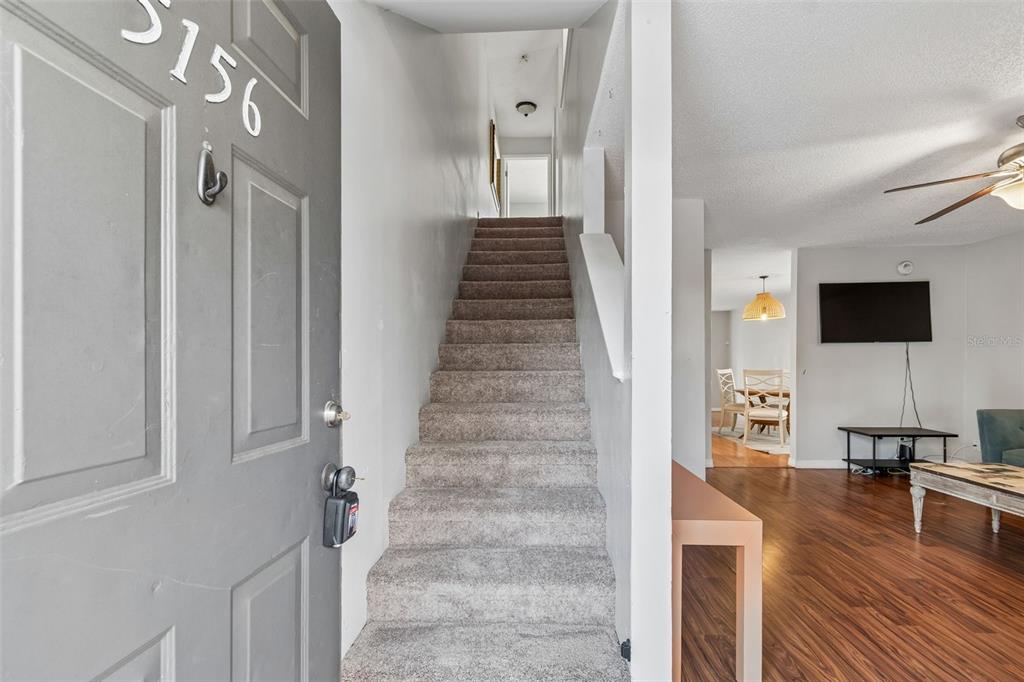 An entryway features a carpeted staircase leading upward next to a living room with flooring — 5156 SUNRIDGE PALMS DRIVE, TAMPA, FL