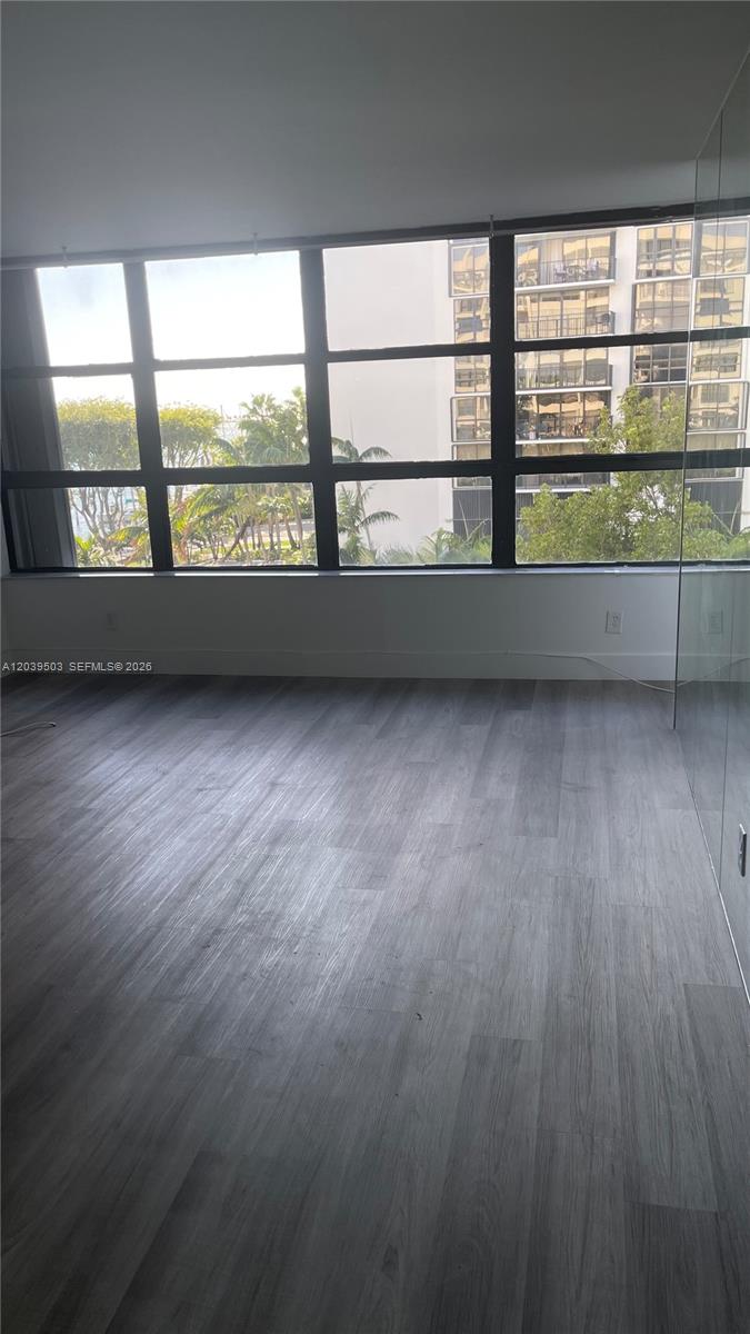 An empty room features gray wood-look flooring and a large window with exterior views — 1440 Brickell Bay Dr # 508, Miami FL 33131, MIAMI, FL