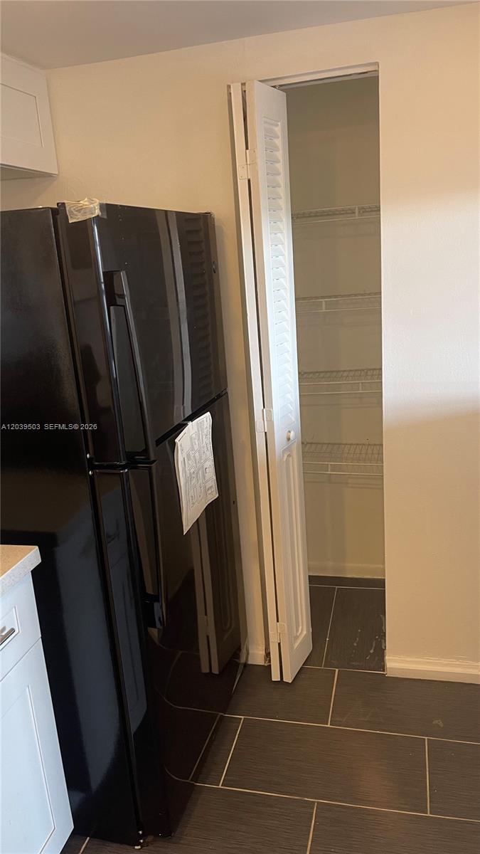 A black refrigerator stands next to an open pantry with wire shelving in a kitchen — 1440 Brickell Bay Dr # 508, Miami FL 33131, MIAMI, FL