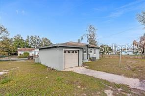 A detached garage sits on a grassy lot next to a small house — 131 W CRYSTAL AVENUE, LAKE WALES, FL