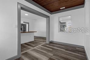 A dining area with wood-look flooring and a wood-paneled ceiling opens into a kitchen — 131 W CRYSTAL AVENUE, LAKE WALES, FL