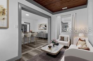 This interior view shows a living room with a wood-paneled ceiling opening into a kitchen — 131 W CRYSTAL AVENUE, LAKE WALES, FL