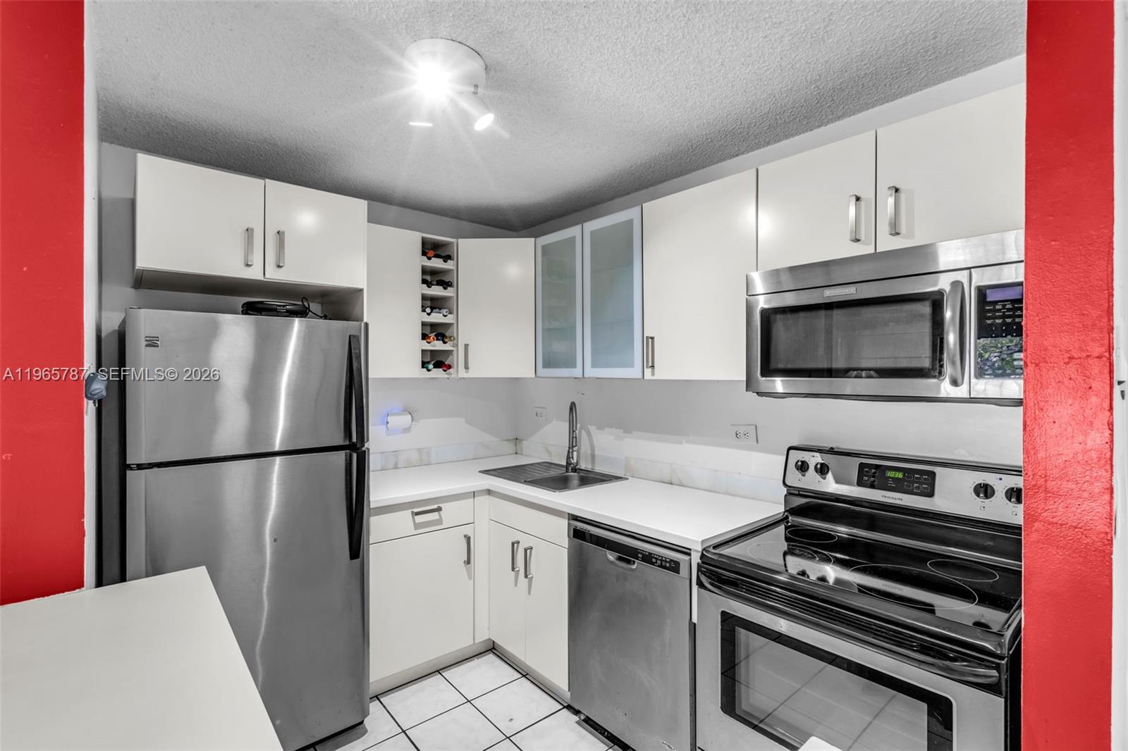 A kitchen features white cabinets, stainless steel appliances, and a tiled floor — 7060 NW 179th St # 210, Hialeah FL 33015, HIALEAH, FL