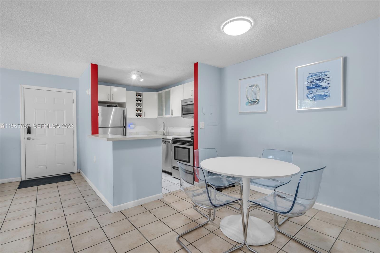 A kitchen with stainless steel appliances and a dining area with clear chairs — 7060 NW 179th St # 210, Hialeah FL 33015, HIALEAH, FL