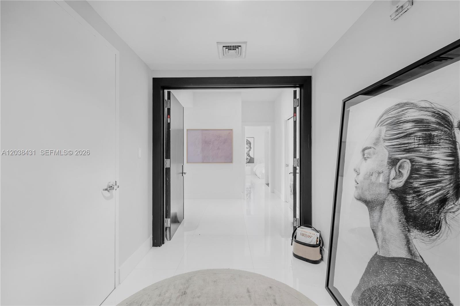 A bright hallway features white tile floors, black door frames, and a large portrait print — 900 Biscayne Blvd # 2302, Miami FL 33132, MIAMI, FL