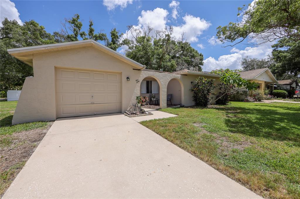 A single-story house with a beige stucco exterior, a one-car garage, and an arched entryway — 160 MEADOWLARK DRIVE, SAFETY HARBOR, FL