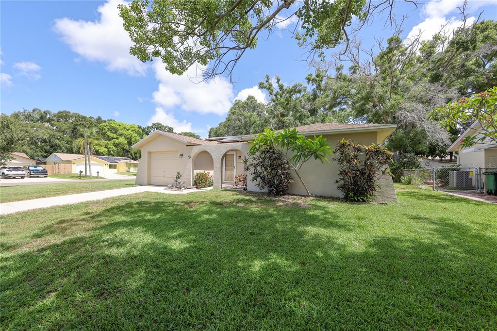 A single-story house with a beige exterior, a one-car garage, and a front lawn — 160 MEADOWLARK DRIVE, SAFETY HARBOR, FL