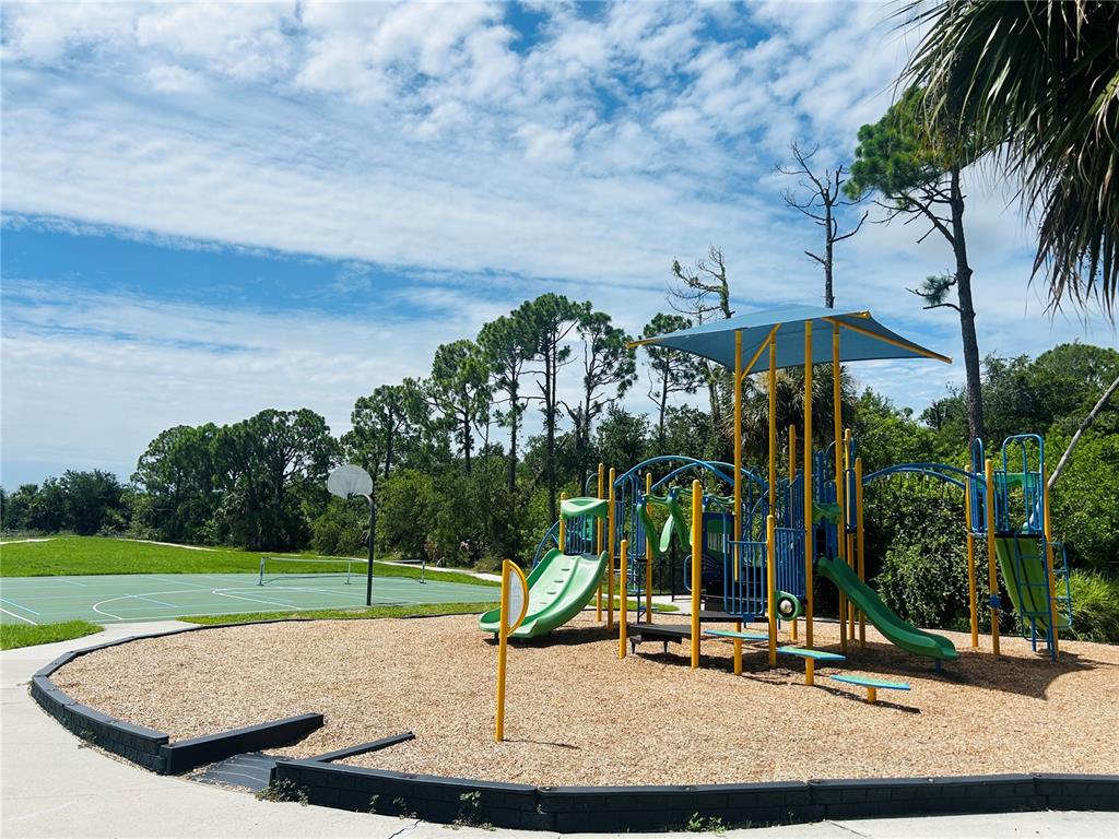 A playground with slides and a canopy sits next to a tennis court outdoors — 15714 STUART CIRCLE, PORT CHARLOTTE, FL