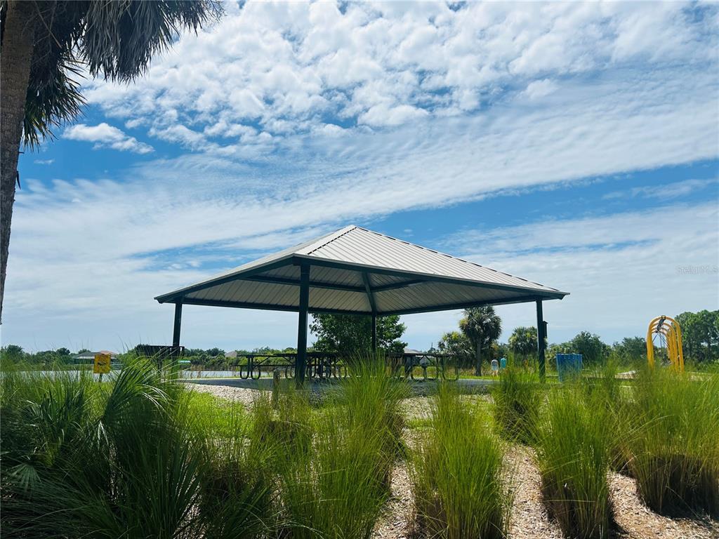 A metal-roofed pavilion with picnic tables sits in a park near a body of water — 15714 STUART CIRCLE, PORT CHARLOTTE, FL