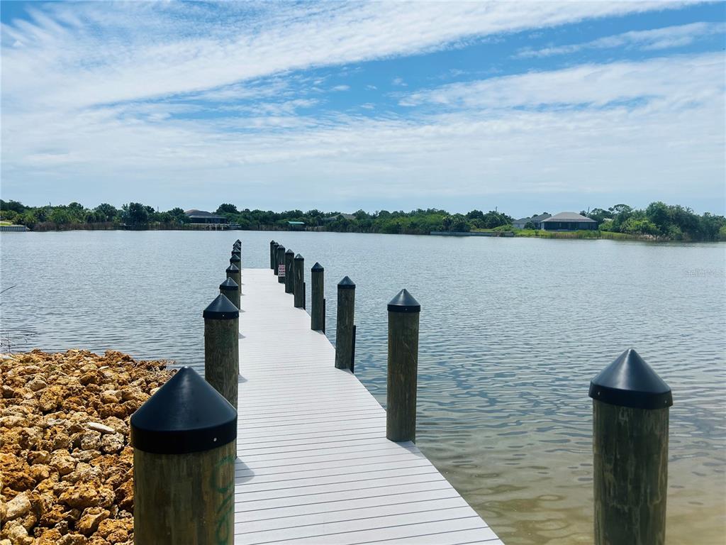 A white dock extends into a calm lake under a blue sky with clouds — 15714 STUART CIRCLE, PORT CHARLOTTE, FL