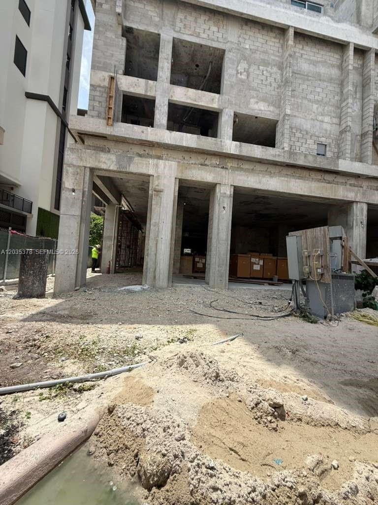 An unfinished concrete building structure stands above a dirt lot with construction equipment — 4011 SALZEDO ST, FL 33146, FL