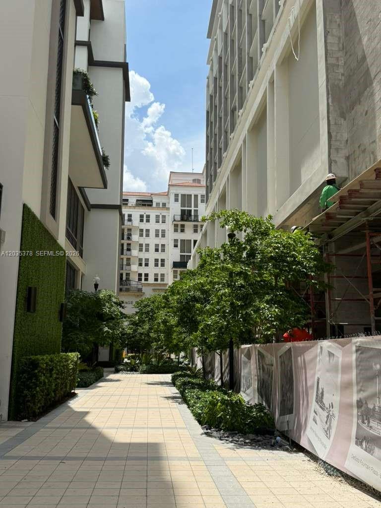 A paved walkway leads between two modern buildings with landscaping and construction scaffolding on the right — 4011 SALZEDO ST, FL 33146, FL